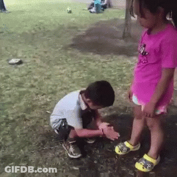 Girl In Pink Shirt Standing Beside Kneeling Boy GIF