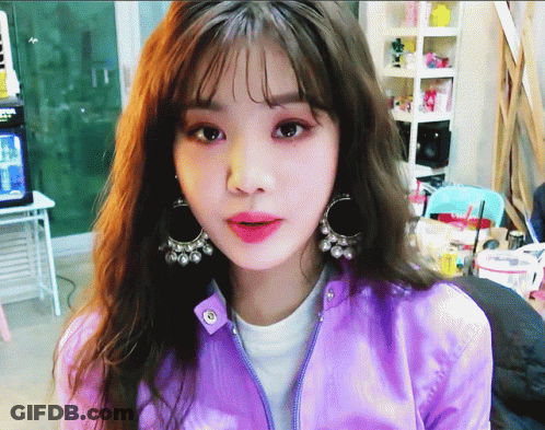 Girl In Purple Jacket And Earrings Looking At Camera GIF