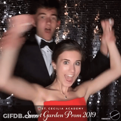 Girl In Red Dress Posing With Man In Tuxedo GIF