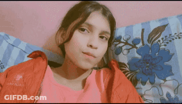 Girl In Red Jacket Lying On Bed GIF