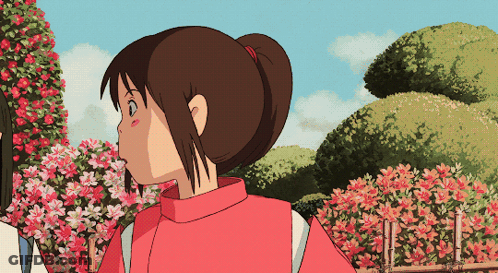 Girl In Red Sweater Standing In Front Of Pink Flowers GIF