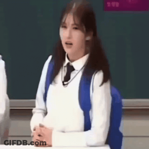 Girl In School Uniform Sitting At Desk With Blue Backpack GIF