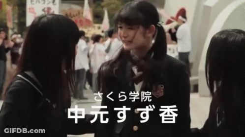 Girl In School Uniform Talking To Girl With Chinese Writing GIF