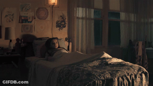 Girl In Striped Shirt Sitting On Bed GIF