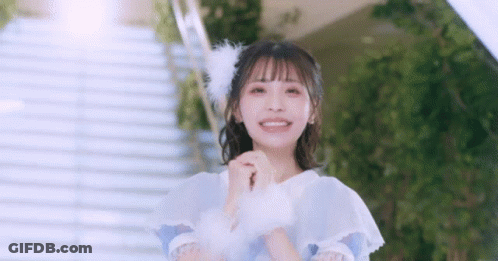 Girl In White Dress With Feathers In Hair Standing In Front Of Stairs GIF