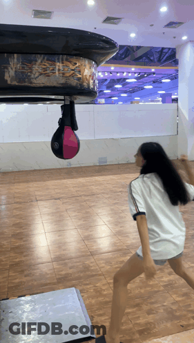 Girl In White Shirt Playing With Punching Bag GIF
