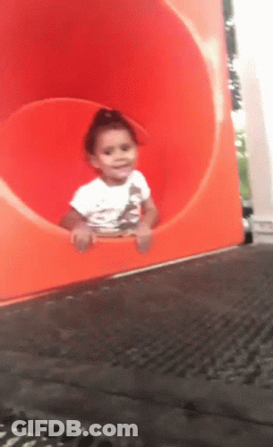 Girl In White Shirt Sitting In Orange Tube Slide GIF