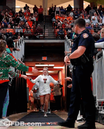 Girl In White Shirt With Letter T Walking Through Crowd GIF