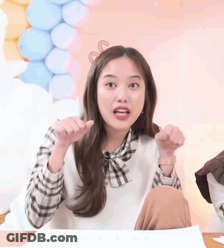 Girl Sitting At Table With Hands In Air GIF