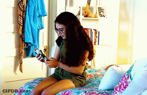 Girl Sitting On Bed Looking At Phone GIF