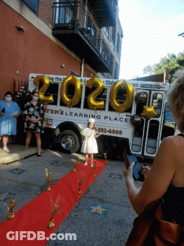 Girl Standing On Red Carpet In Front Of Bus GIF