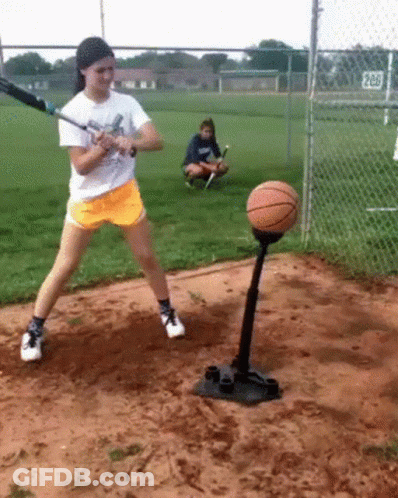 Girl Swinging Baseball Bat At Basketball On Tee GIF