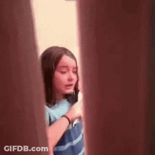 Girl Talking On Cell Phone Behind Door GIF
