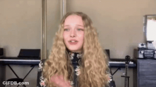 Girl With Blonde Hair Standing By Piano And Guitar GIF