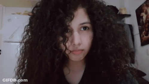 Girl With Curly Hair Looks At Camera GIF