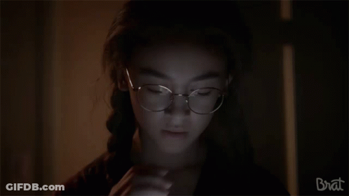 Girl With Glasses Looking In Dark Room GIF