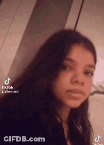 Girl With Long Dark Hair Looking At Camera GIF