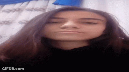 Girl With Long Dark Hair Taking Selfie Blue Curtain GIF