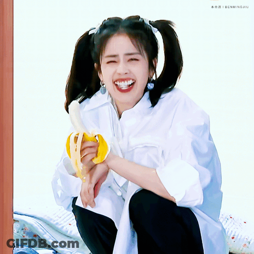 Girl With Pigtails Smiling Holding Banana GIF