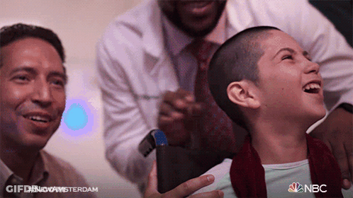 Girl With Shaved Head Laughing Held By Two Men NBC Logo GIF