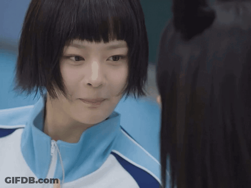 Girl With Short Black Hair And Blue Jacket Looks At Another Girl GIF