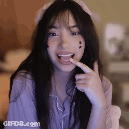 Girl With Star Face Smiling And Licking Finger GIF