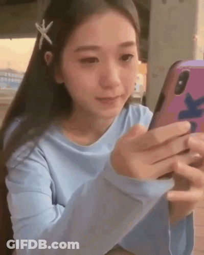 Girl With Starfish In Hair Looking At Cell Phone GIF