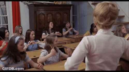 Girls Sitting At Desks In Classroom With Teacher GIF