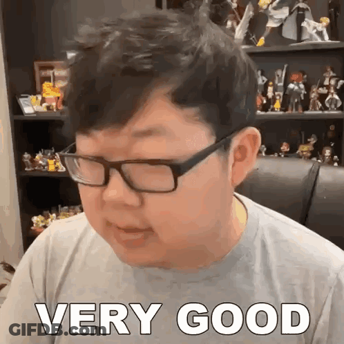 Glasses Man Says Very Good With Figurine Shelf GIF