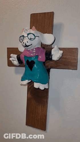 Goat Statue With Glasses Sitting On Cross GIF