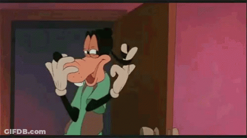 Goofy From Mickey Mouse Is Standing In Front Of A Door And Talking On A Cell Phone . GIF
