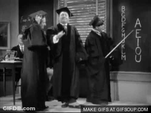 Graduation Gowns Standing In Front Of Blackboard GIF