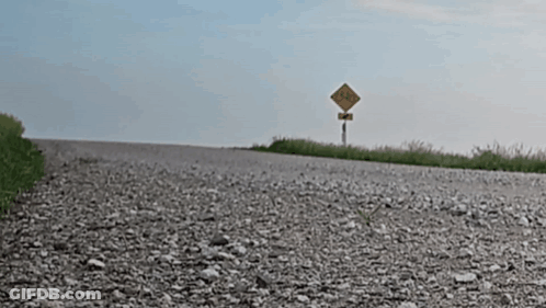Gravel Road With Yellow No Trucks Sign GIF