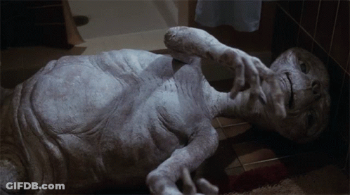 Gray Alien Lying On Floor Hands Out GIF