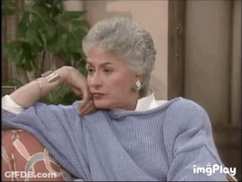 Gray-Haired Woman Sitting On Couch With Hand On Chin GIF