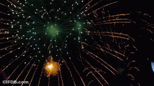 Green And Gold Fireworks In The Night Sky With A Boat In The Background GIF