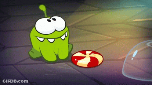 Green Cartoon Character Sitting Next To Red Candy GIF