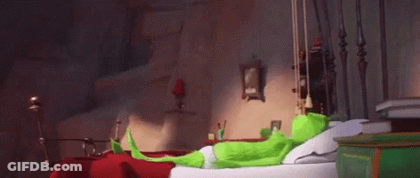 Green Cartoon Character Sitting On Bed In Bedroom GIF