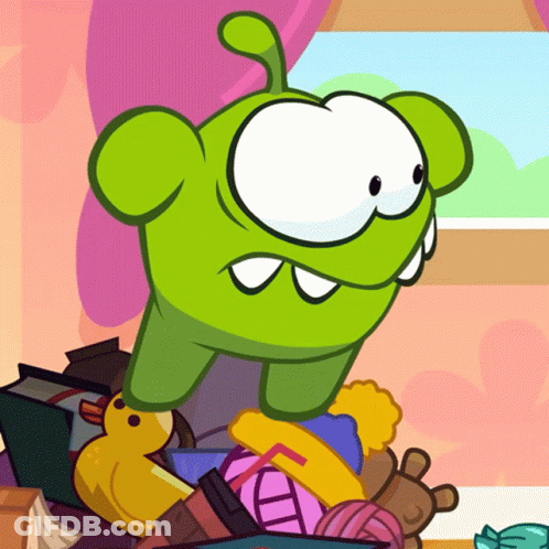 Green Cartoon Character Sitting On Toys GIF