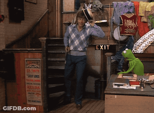 Green Kermit The Frog Standing In Front Of Exit Sign GIF