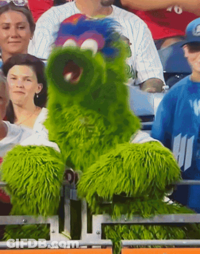 Green Monster Mascot Sitting In Stands At Sports Game GIF