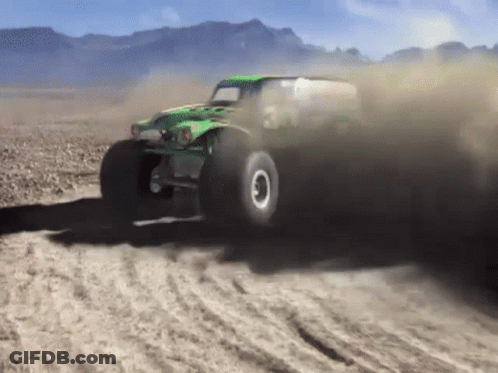Green Monster Truck Driving On Dirt Road With Mountains GIF