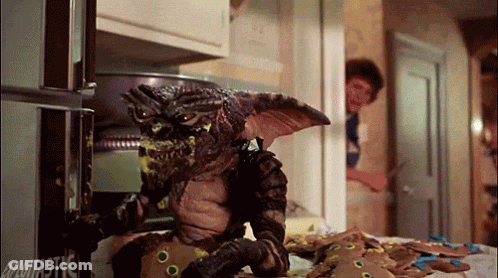 Gremlin Eating Gingerbread Cookies In Front Of Glotastic Refrigerator GIF