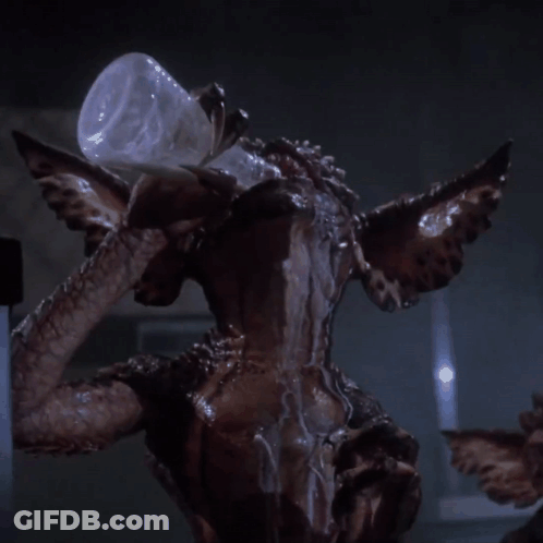 Gremlin Holding Glass Bottle In Mouth GIF