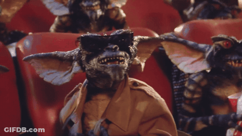Gremlins Sitting In Red Chairs Eating Popcorn GIF