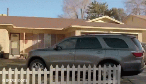 Grey SUV Parked In Front Of White Picket Fence GIF
