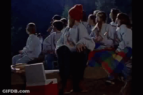 Group Around Campfire Woman On Cooler GIF