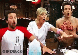 Group Around Table With Man Wearing Go Phils Shirt GIF