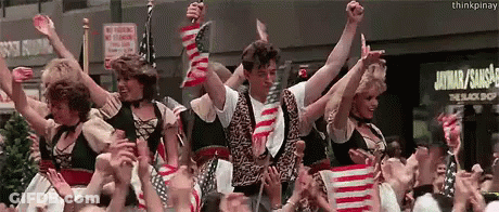 Group Holding American Flags At The Black Shop Sign GIF