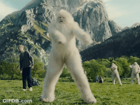 Group In Grassy Field With Mountains And Bigfoot Costume GIF